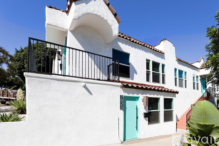 A white house with a blue door and a balcony.