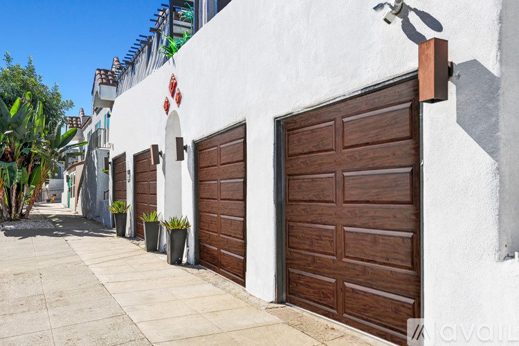 A white building with a brown door and a balcony above it.