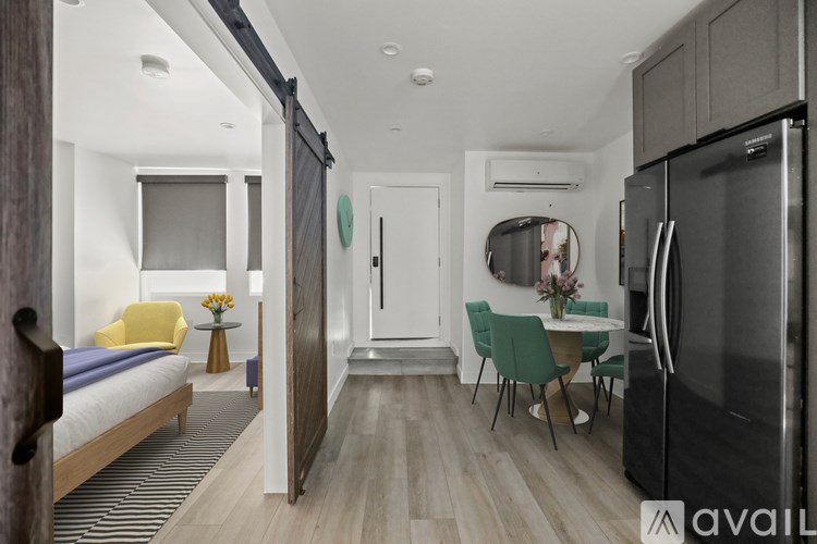 A kitchen with a refrigerator, table and chairs, and a bedroom with a bed and a window.