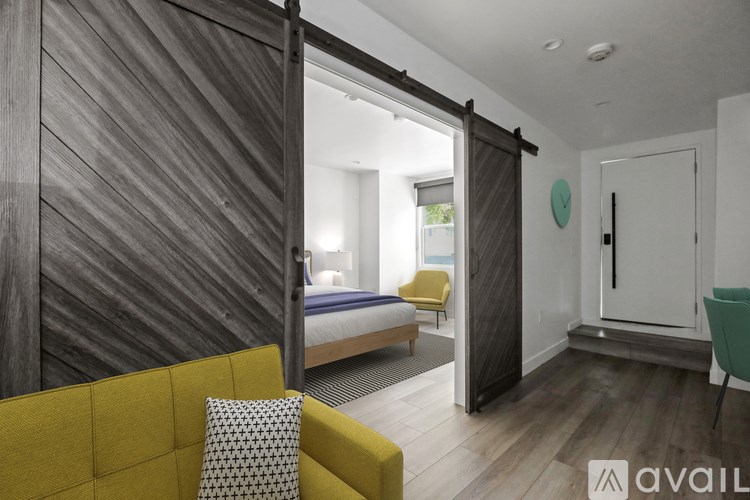 A room with a yellow couch and a bed in the background.