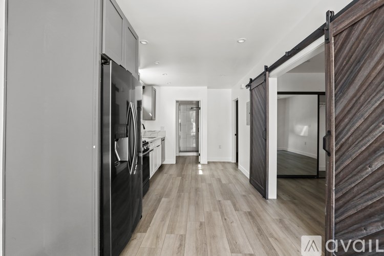 A modern kitchen with a refrigerator, oven, and wooden flooring.