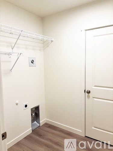 A white door is on the right side of a room with a white wall and a white closet rod.