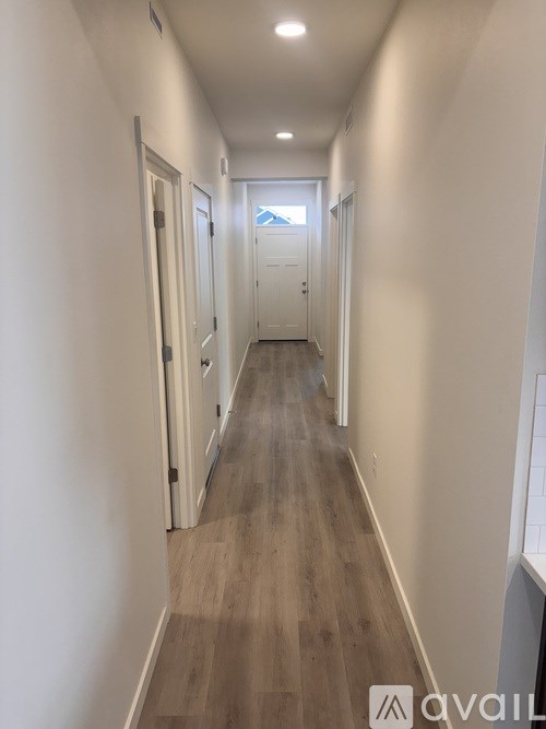 A long hallway with doors on both sides and a light at the end.