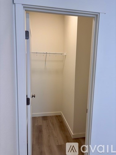 A white door is open to a room with a wooden floor.