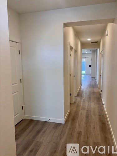 A long hallway with wood floors and white walls.