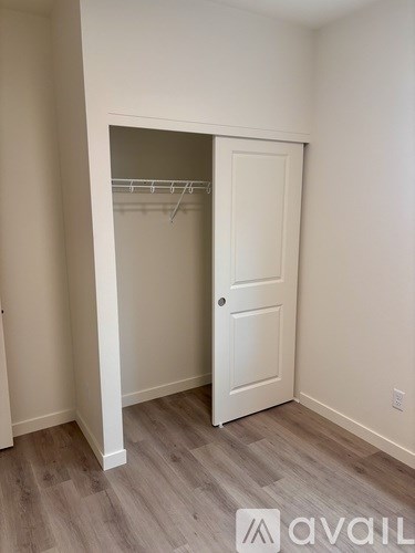 A room with a white door and a white closet with clothes hangers.