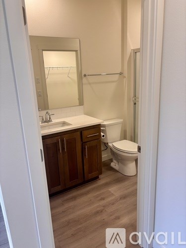 A bathroom with a toilet, sink, and mirror.