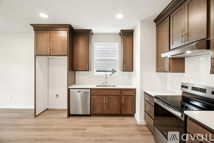 A kitchen with wooden cabinets and a stainless steel dishwasher.