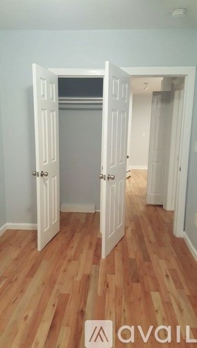 A room with wooden floors and two open doors.