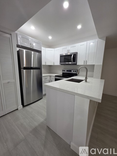 A modern kitchen with a stainless steel refrigerator and white cabinets.