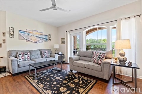 A living room with a grey couch and a black and white rug.
