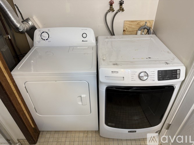 A white dryer and washing machine are in a small room.