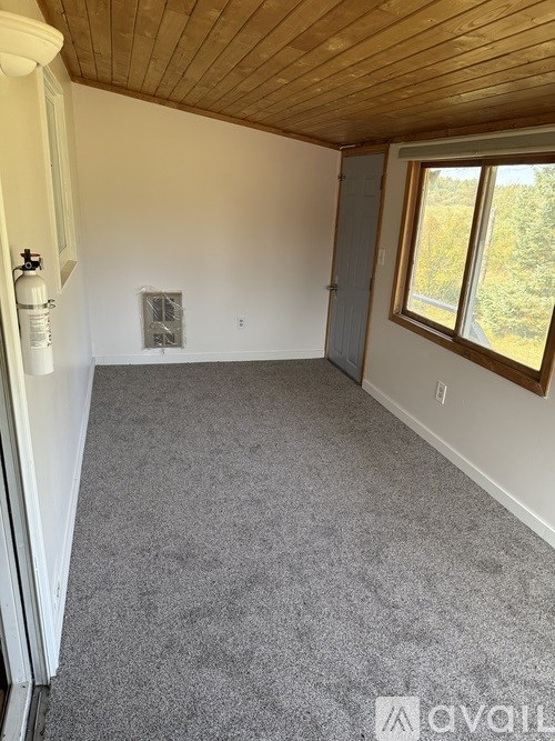 A room with a grey carpet and a wooden ceiling.