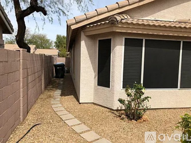 A house with a brown wall and a small tree in front.
