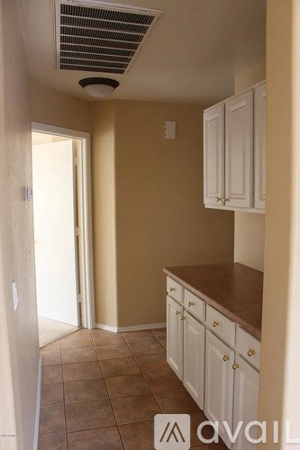 A kitchen with white cabinets and a brown countertop.