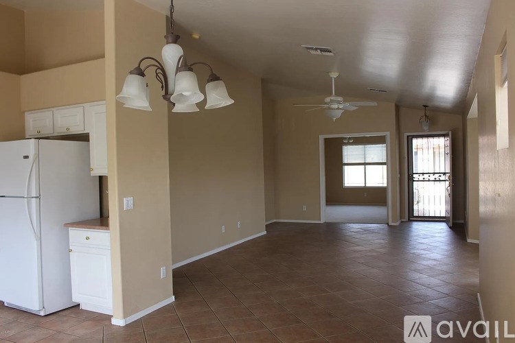 A kitchen with a white refrigerator and brown tile flooring.