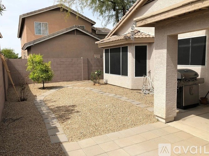 A backyard with a gravel area and a small tree.