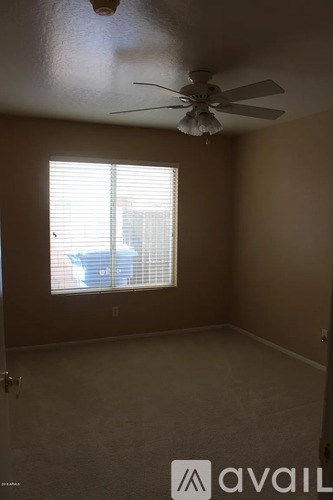 A room with a ceiling fan and a window with blinds.