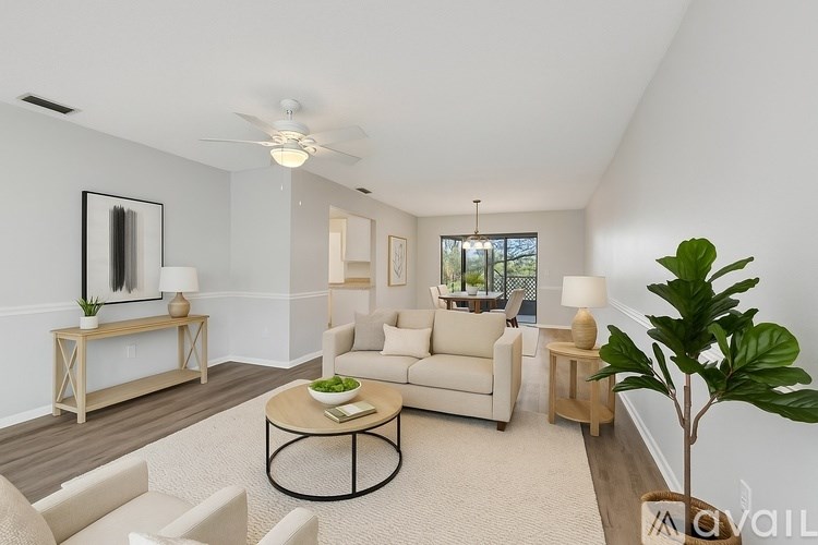 A living room with a white couch, a coffee table, and a plant.