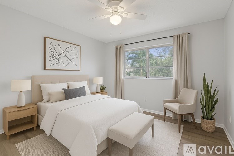 A bedroom with a large bed, a ceiling fan, and a chair.