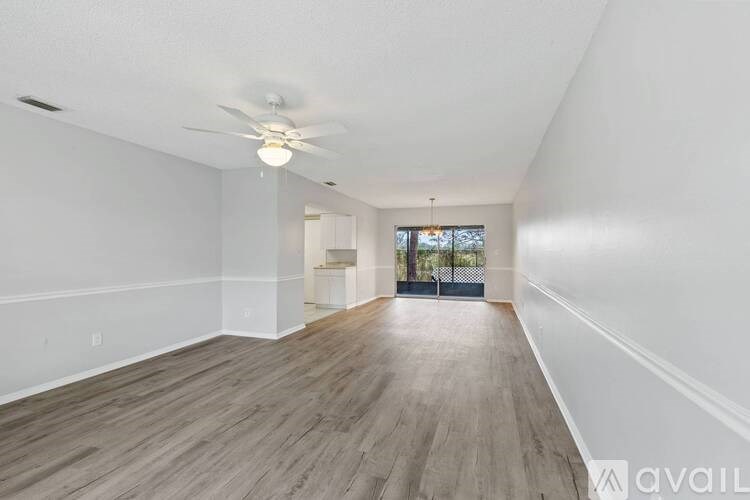 A spacious room with wooden flooring and a ceiling fan.
