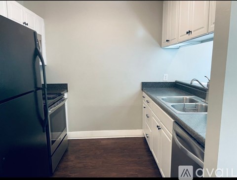 A kitchen with a black fridge and white cabinets.