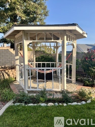 A gazebo in a garden with a white railing and a white roof.