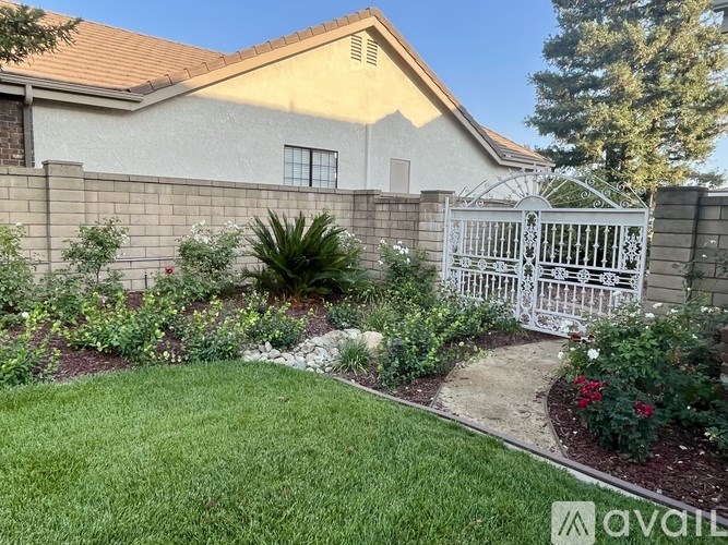 A white gate leads to a house with a well-kept garden.