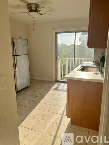 A kitchen with a refrigerator, sink, and ceiling fan.