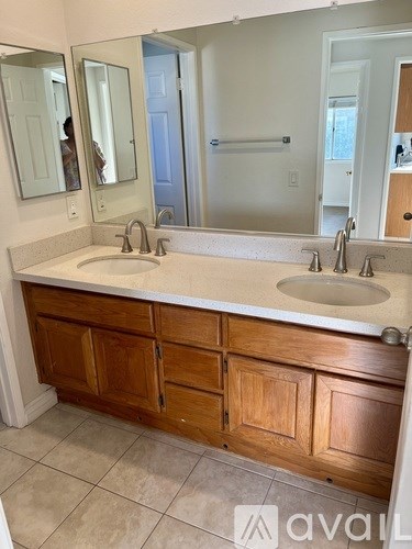 A bathroom with a white counter top and wooden cabinets.