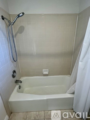 A white bathtub with a shower head and a white curtain.