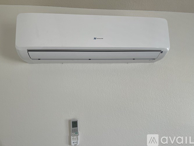 A white air conditioner is mounted on a white wall.