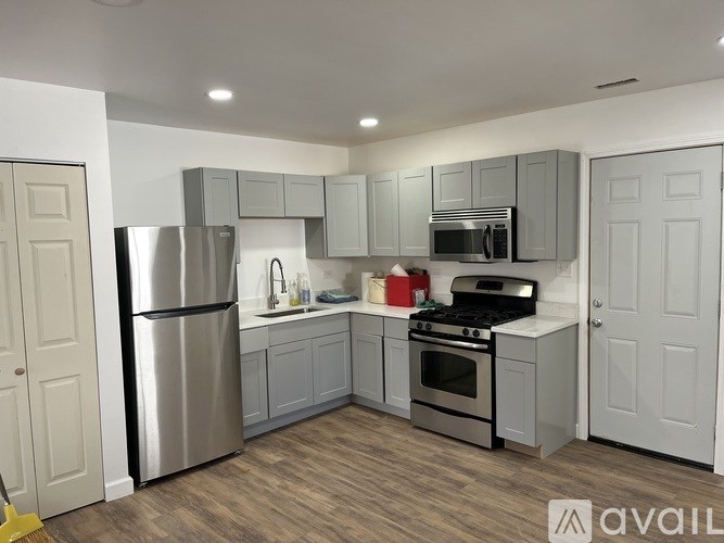 A modern kitchen with stainless steel appliances and wooden flooring.