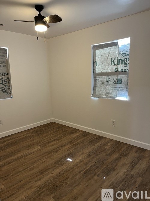A room with a ceiling fan and wooden flooring.