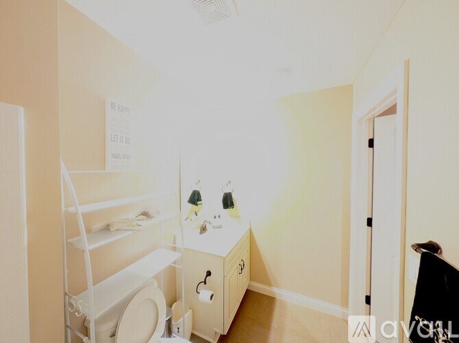 A bathroom with a toilet, sink, and a white shelf.