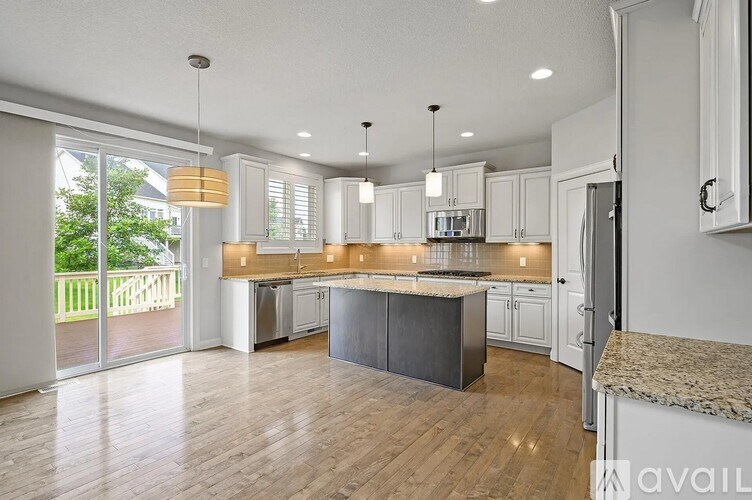 A modern kitchen with a center island and pendant lights.