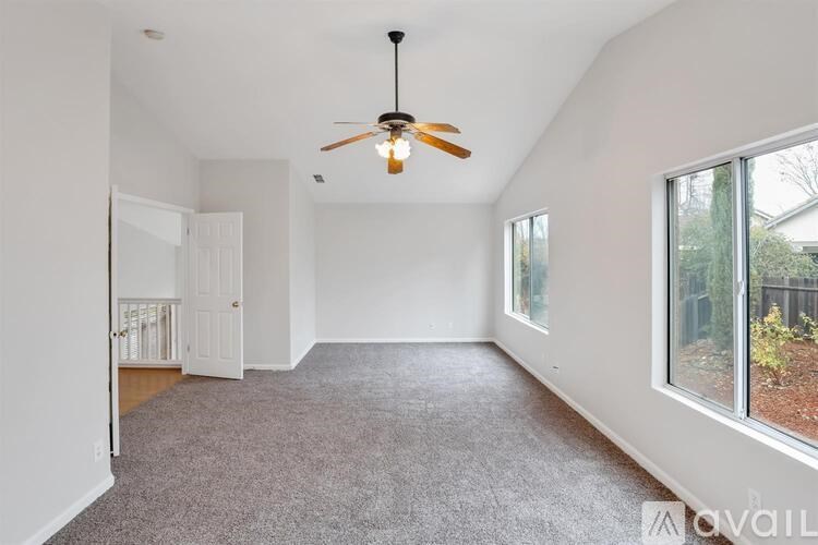 A spacious room with a ceiling fan and carpeted floor.