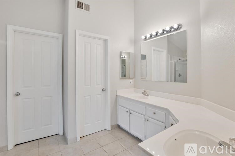 A white bathroom with a tub, sink, and two doors.