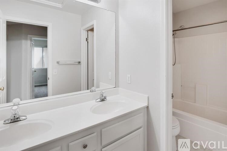 A white bathroom with a double sink vanity and a bathtub.