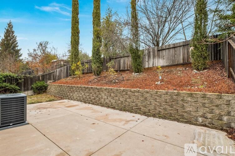 A backyard with a stone wall and a fence.