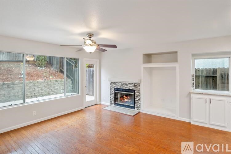 A living room with a fireplace and a fan.