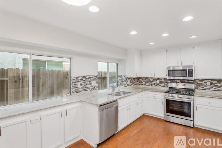 A kitchen with white cabinets and a marble backsplash.