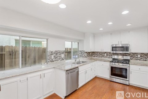 A kitchen with white cabinets and a marble backsplash.