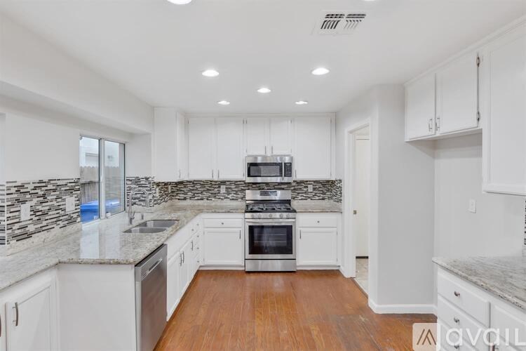 A kitchen with white cabinets and a stone backsplash.
