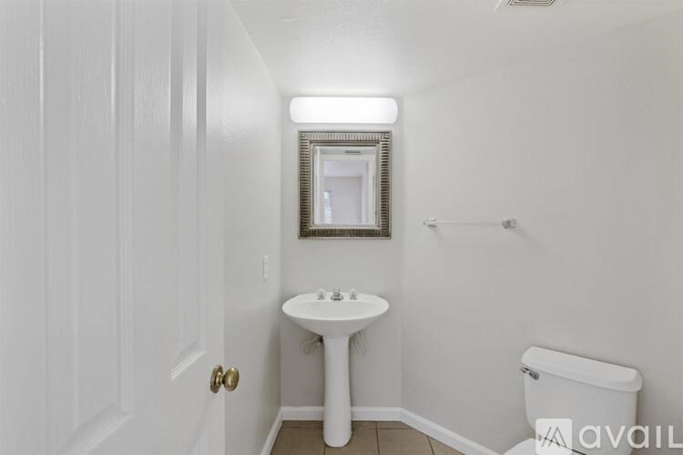 A small white bathroom with a toilet, sink, and mirror.