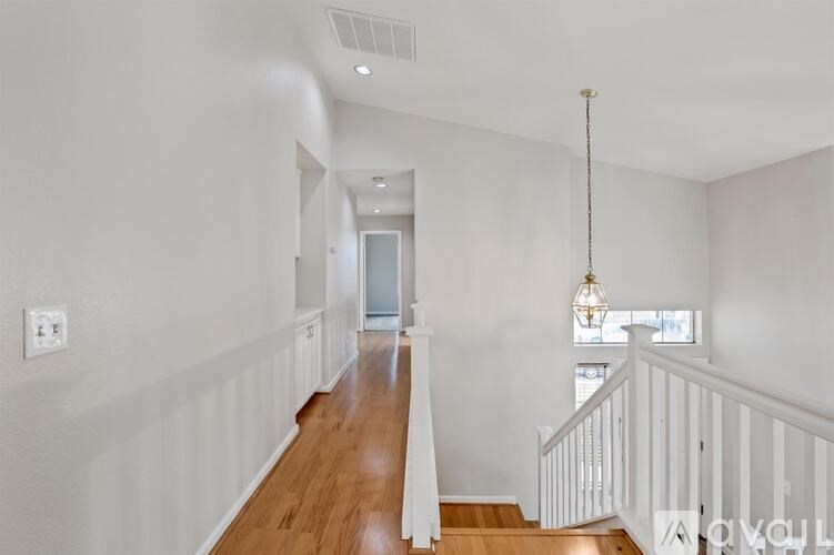 A long hallway with a white railing and wooden floors.
