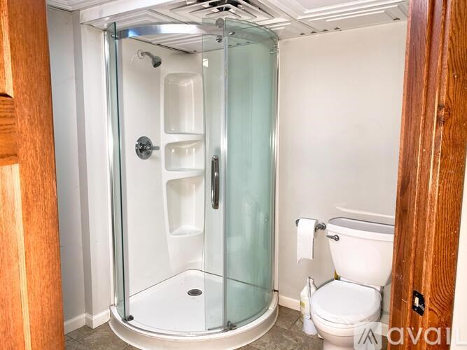 A glass shower stall with a white toilet in the corner.