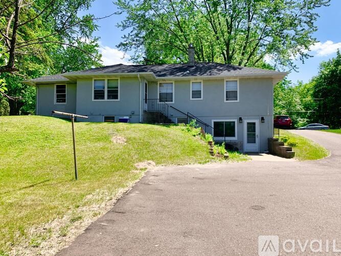 A house with a grey roof and a white garage door is surrounded by greenery.