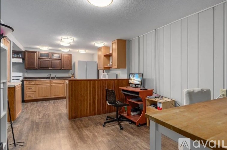 A kitchen with wooden cabinets and a desk with a computer.