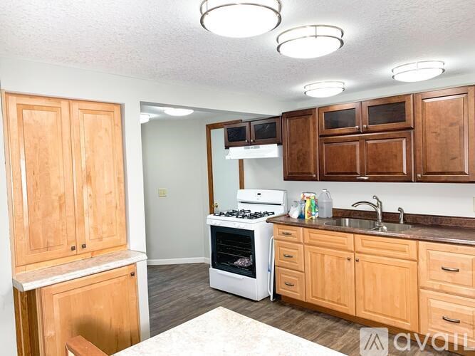 A kitchen with wooden cabinets and a white stove top oven.